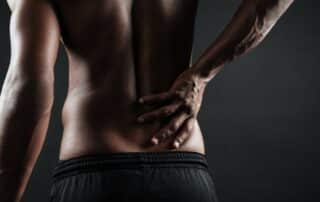 man holding his lower back indicating acute or chronic pain