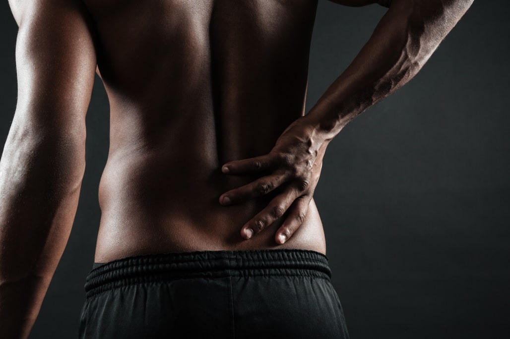 man holding his lower back indicating acute or chronic pain