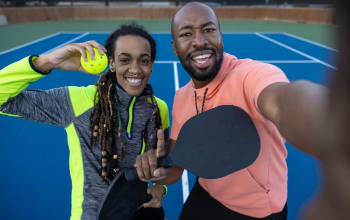 athletic couple posing on pickleball court, avoiding pickleball injuries