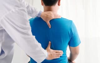 Man getting his back assessed for surgery to improve his spinal stenosis.